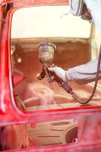 paint engineer working on red car in painting booth