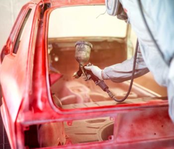 paint engineer working on red car in painting booth