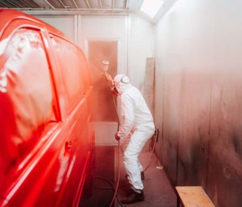 automotive industry manufacturing - mechanic engineer using spray gun and painting a red car