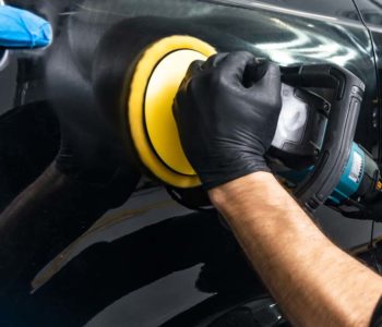 Car polish wax worker hands applying protective tape before polishing. Buffing and polishing car. Car detailing. Man holds a polisher in the hand and polishes the car. Tools for polishing